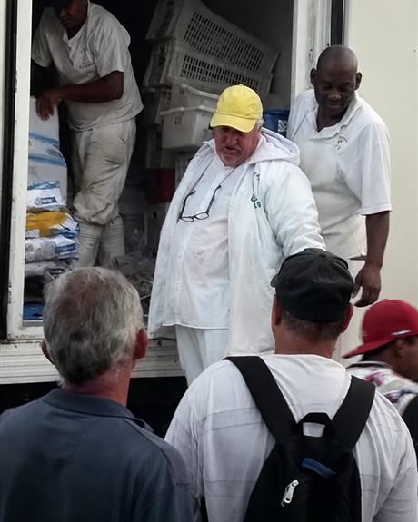 Descarregamento de pescado em caminhão frigorífico, com trabalhadores do setor.